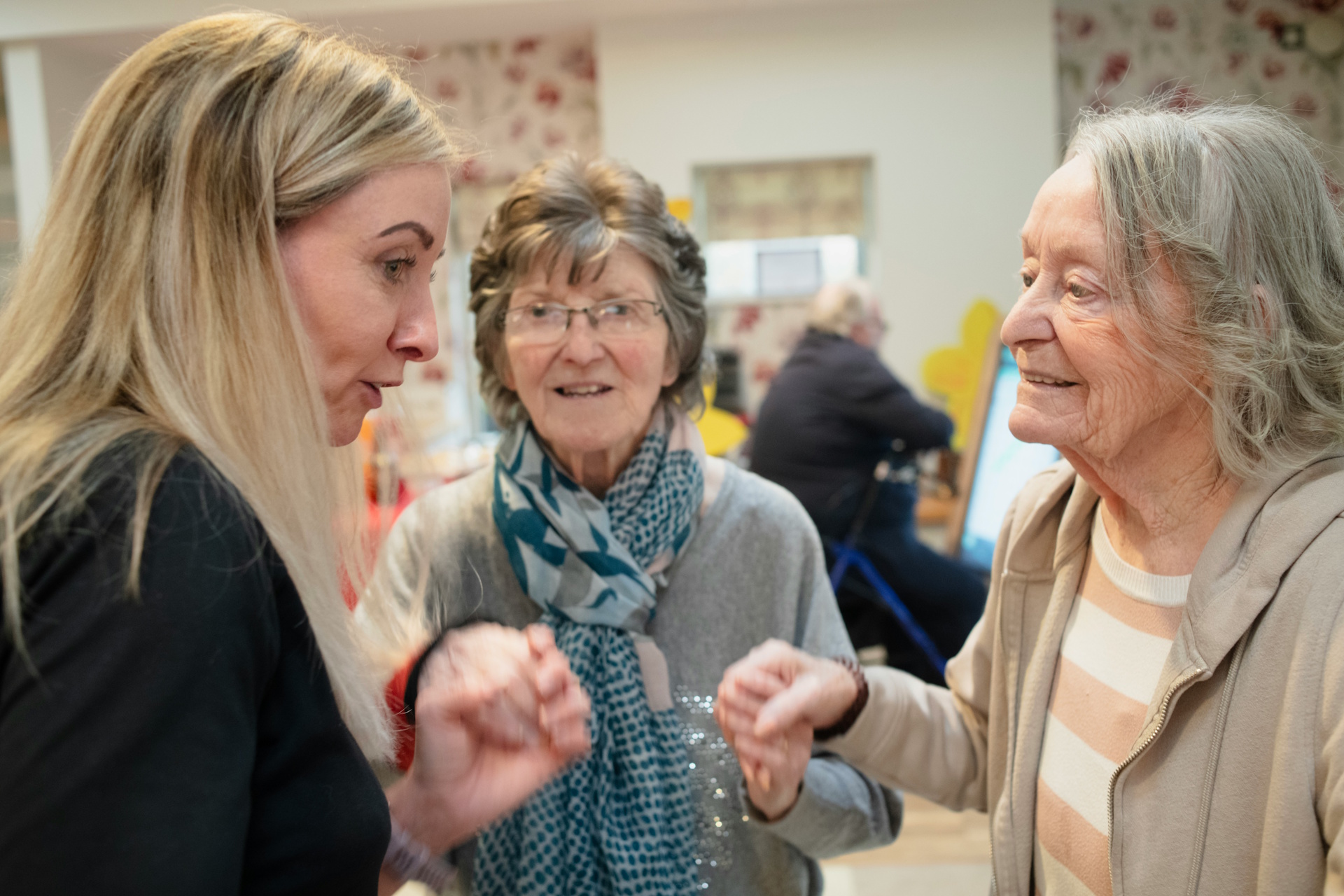 Residents and carers chatting in a bright communal lounge